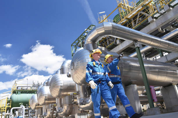 group of industrial workers in a refinery oil processing equipment and machinery group of industrial workers in a refinery oil processing equipment and machinery